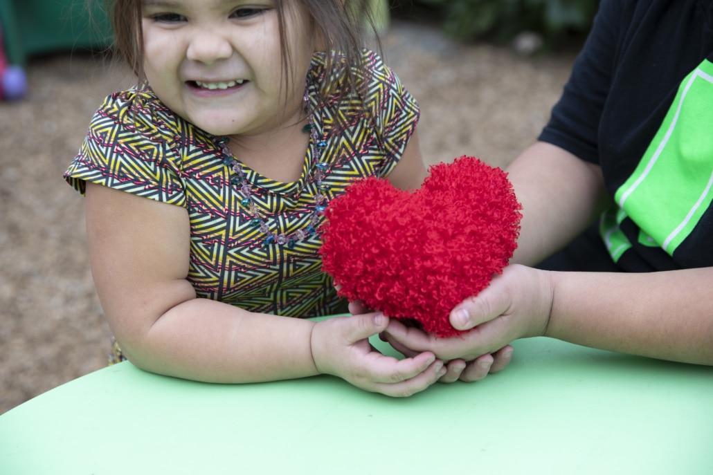 Sonoma County Vintners Foundation little girl beneficiary smiling and holding a plush heart