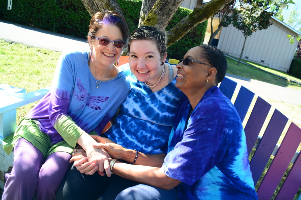 Three women sitting on a bench smiling