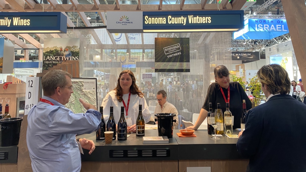 Sonoma County Vintners at Prowein two women behind a wine tasting booth with a man on the other side talking to them
