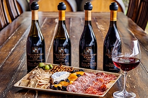 Four bottles of Papapietro Perry behind a charcuterie plate